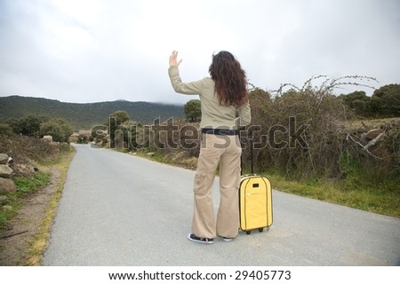 woman with suitcase on rural road at gredos mountains in avila spain