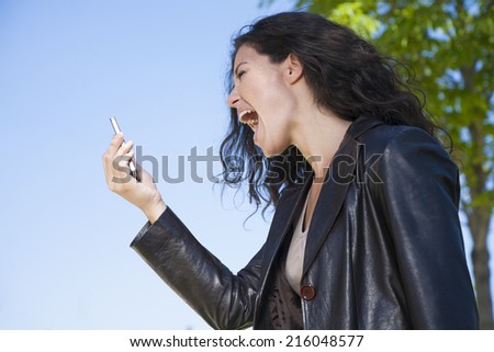 woman shouting in video call smartphone at exterior background