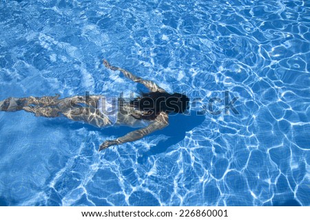 woman with white bikini diving at the bottom of a blue pool