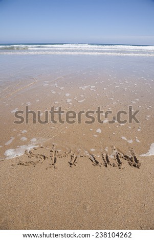 ocean water flood Spain word written on brown sand ground beach seashore
