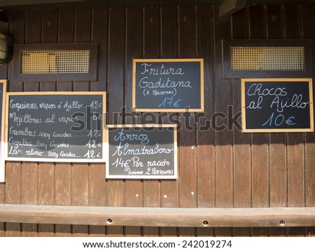 four black placards spanish handwritten in brown wood wall with typical menu food dishes in Spain restaurant