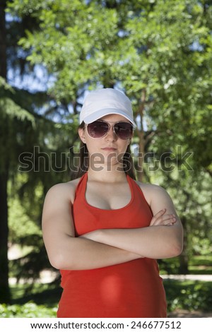 portrait of young pregnant woman with red shirt threatening face and green trees background