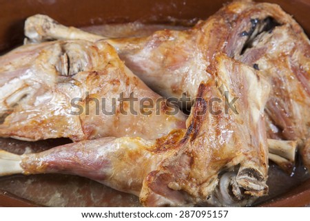 spanish roast leg of baby lamb in ceramic tray on brown linen tablecloth