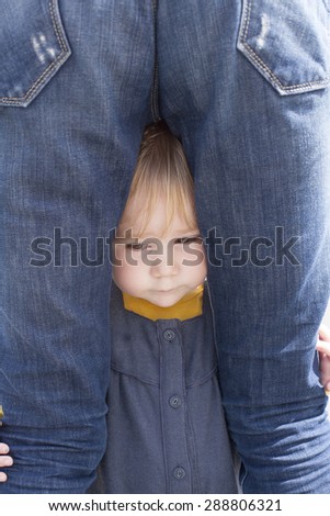 blonde nineteen month age baby with blue and yellow dress between mother blue jeans back woman legs