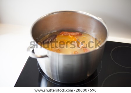 big silver metal pan with typical spanish food stew with beans native from Asturias black pudding sausage on black cooker in white kitchen