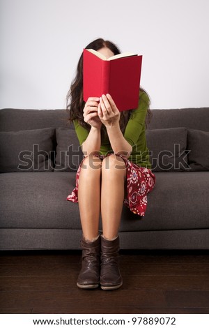 woman detail sitting on a brown sofa reading a book - stock photo