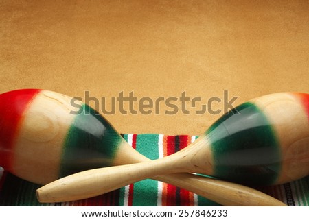 Maracas and colorful Mexican blanket on brown suede surface