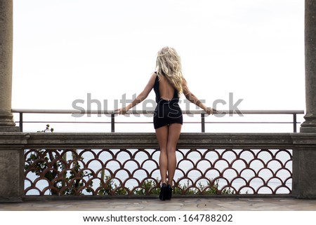 Beautiful photo of sexy blonde woman standing back. Girl with long curly hair.