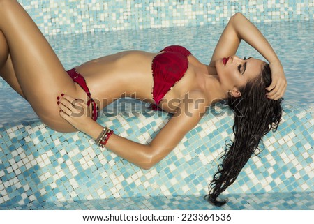 Sexy brunette beautiful woman with perfect body lying in water, relaxing