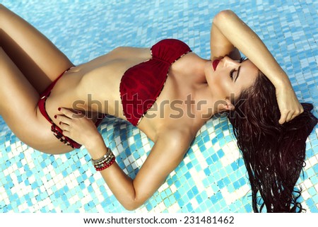 Sexy beautiful brunette woman with perfect body lying in water, sunbathing.