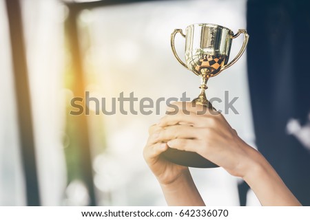 Teenage girls\' hands are holding trophies, congratulations on success.Conception of victory in the competition.Focus on the trophy