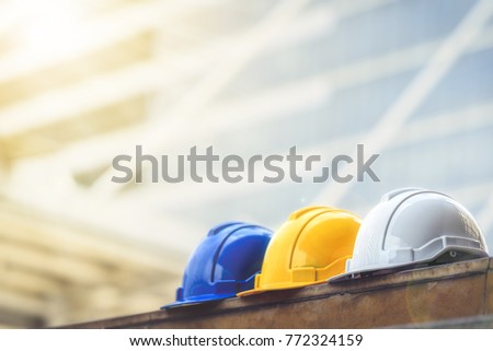 white, yellow and blue hard safety helmet hat for safety project of workman as engineer or worker, on concrete floor on city.