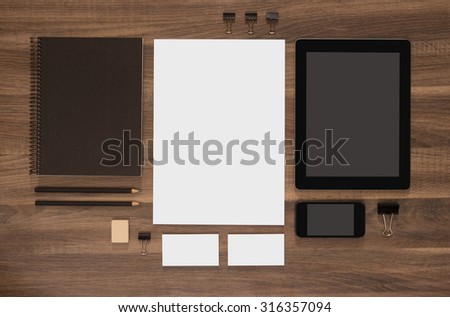 Branding mockup set on brown wooden desk. Blank business cards with mobile and tablet. White document.