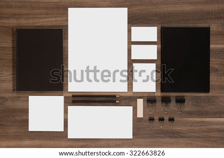 Set of branding mockup on brown wooden desk. Blank business cards with documents, paperclips and black notepads.