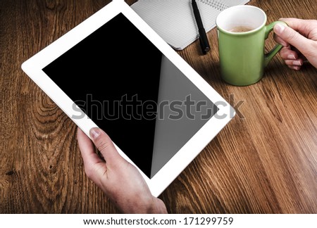 Tablet computer cup of coffee and notepad at table Tablet computer cup of coffee and notepad at table