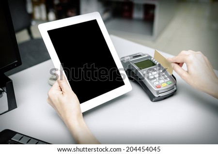 Female hand holding  bank terminal and tablet pc