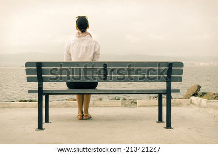 Lonely woman sitting on a bench by the sea Lonely woman sitting on a bench by the sea