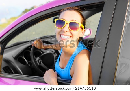 Beautiful girl in a car smiling in pink sunglasses