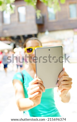 Tourist smiles and holds tablet computer in hands. Focus on tablet.