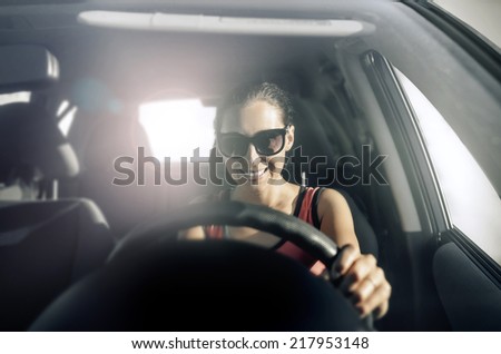 Woman drives a car in the rays of bright light