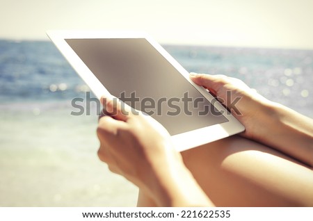 Woman with tablet pc at the beach. Vintage photo.