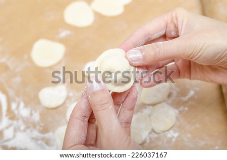 Hands of a woman who molds dumplings on kitchen table
