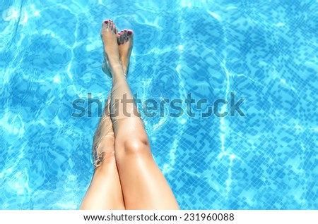 Female legs in the pool water