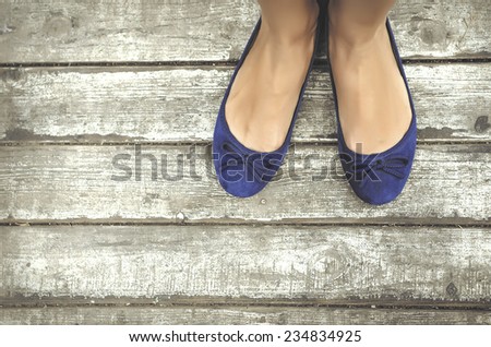 Girls beautiful blue shoes over wooden deck.
