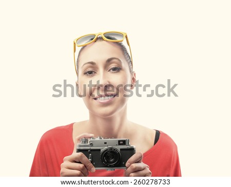 Girl with the retro camera. Beautiful girl in red, the camera shoots. Toned photo.