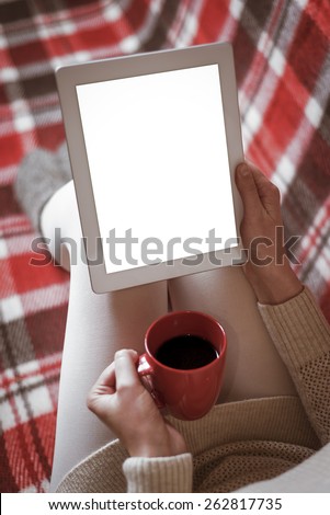 Woman on the sofa with tablet and cup of coffee in hands. Toned photo.