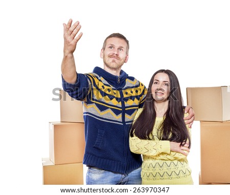 Moving a new family.  Man and woman looking at a wall on the background of boxes in an empty room.