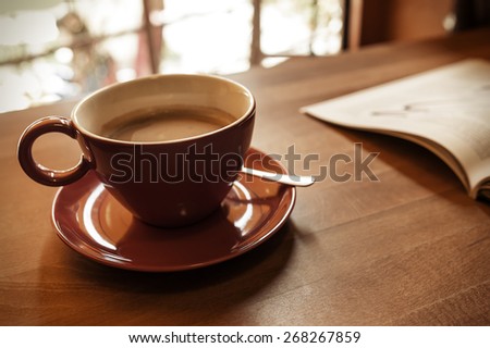 Cup of coffee and a magazine on the table in the cafe. Toned photo.