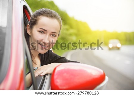 Happy smiling woman in a red car. At sunset. Travel concept.