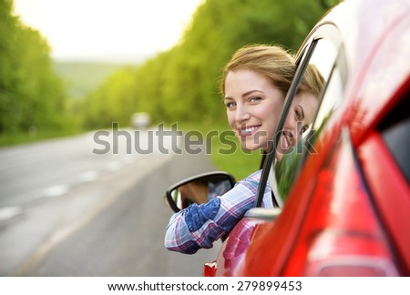 Happy smiling girl in a red car. At sunset. Travel concept.