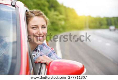 Happy smiling girl in a red car at sunset. Travel concept.