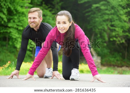 Young sport couple in starting position prepared to compete and run.