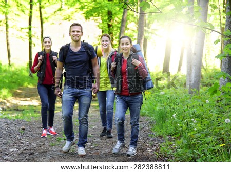 Friends walking in spring forest. Hikers in forest at sunset.