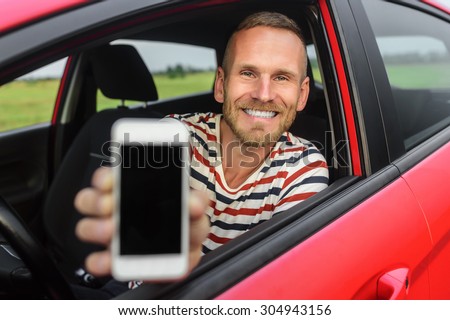 Man in car showing smart phone display smiling happy. Focus on model.
