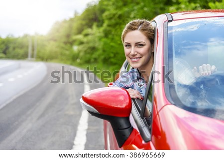 Smiling young pretty woman in the red car. Concept of travel, rent car or buying car.