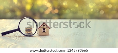 house and money. toy house, magnifying glass and coins. concept of mortgage, construction, rental housing. soft selective focus. banner