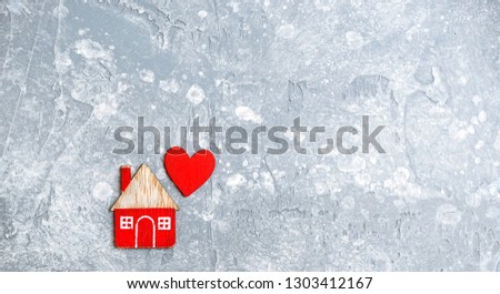 home and red heart, symbol of love, family. design for Valentine's day greetings background. Wooden toy house on grey background. Concept of cozy, loving, protecting, cozy home, care, insurance