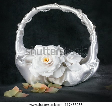 basket of roses wedding of white textile roses with yellow petals decorated with white ribbons, satin shiny white pearls with the petals of roses with a dark grey pearl background