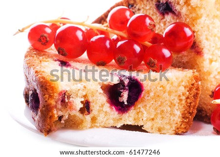 Berry fruitcake with a cherry and a currant, with an appetizing crust and poured by sugar with fresh berries of a red sour currant on a white plate isolated on a white background