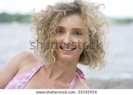 stock photo Portrait Of A Mature Blonde Woman With Curly Hair Near Water