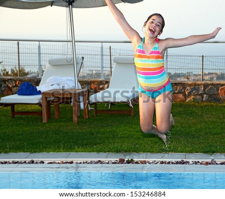 Teenage girl jumping into the pool - Twelve year old girl in the air having a great time jumping into the swimming pool