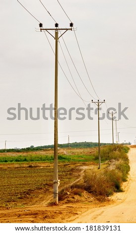 Wooden rural low-voltage electricity pylon / power pole near a dirt road in an Israeli Kibbutz