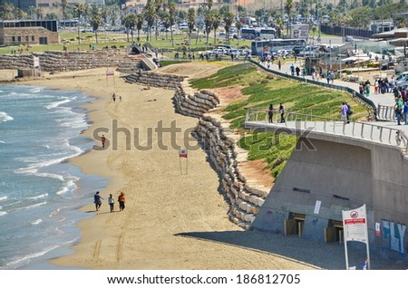 TEL AVIV, ISRAEL - APR 11, 2014: People on the Mediterranean  beach and Tel Aviv, Israel boardwalk with the city sky line and towers in the background