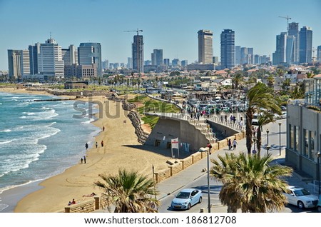 TEL AVIV, ISRAEL - APR 11, 2014:People on the Mediterranean  beach and Tel Aviv, Israel boardwalk with the city sky line and towers in the background on a late spring / early summer day