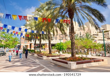 KFAR SABA, ISRAEL - APR 25, 2014: Unidentified people on a main street in Kfar Saba, a suburb of Tel Aviv, decorated with Israeli flags in white and blue for Israel's Independence Day (Yom Haatzmaut)