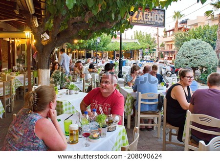 HERSONISSOS, GREECE - JULY 22, 2014: Creten Dinner Time - People eating dinner outdoors in Greek Tavernas at Hersonissos Old City Square in Crete, Greece
